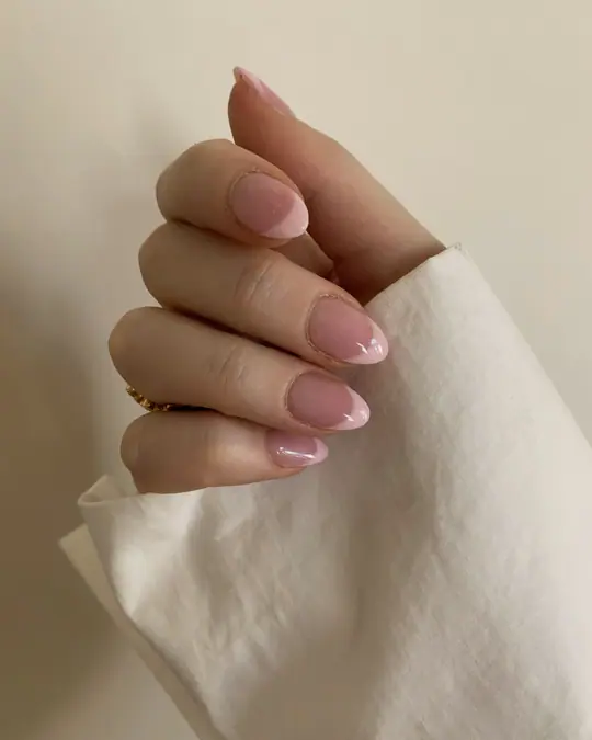 Mano con manicure color nude che stringe un telo di lino